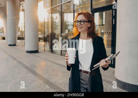 Le modèle femelle contient un bloc-notes à pavé tactile et une tasse de café à emporter en plein air par temps ensoleillé Banque D'Images