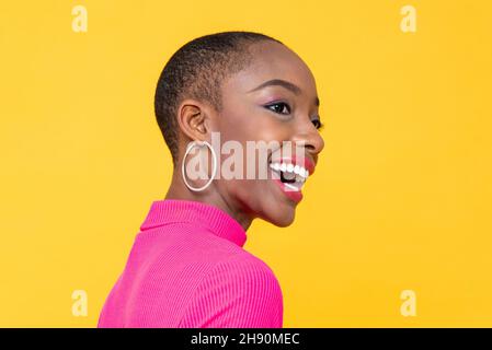 Heureuse souriante belle femme afro-américaine regardant loin dans isolé sur fond jaune studio Banque D'Images