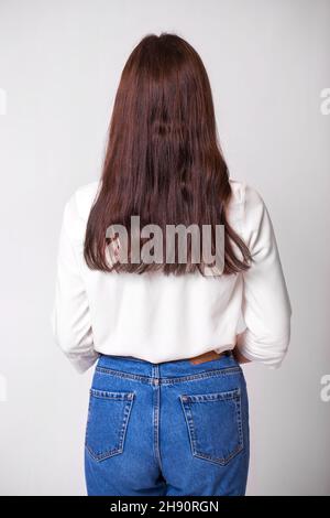 Femme long brunette cheveux, vue arrière, sur fond de mur de studio Banque D'Images