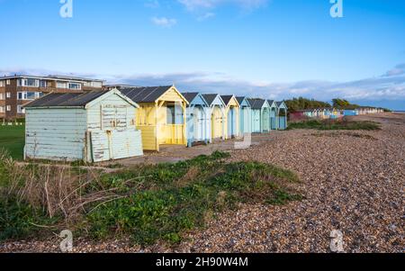 Des cabanes de plage en bois colorées sur le front de mer sur la plage de galets le long de la côte sud à Rustinington, West Sussex, Angleterre, Royaume-Uni. Banque D'Images