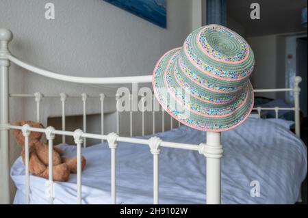 Chapeau d'été coloré sur cadre de lit rétro blanc avec peluche ours en peluche. Banque D'Images