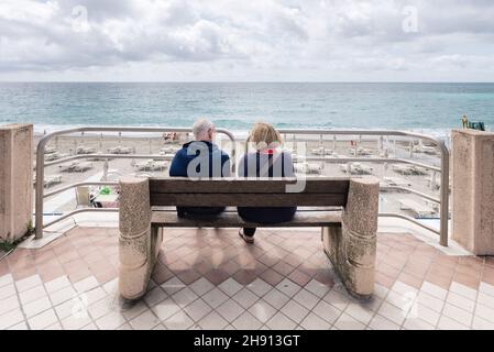 Couple méconnaissable de personnes âgées, mari et femme, vu de derrière, assis sur un banc qui donne loin de la mer et de l'horizon.Les aînés vivent Banque D'Images