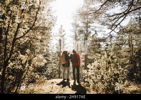 Vue arrière d'un couple debout en forêt par beau temps Banque D'Images