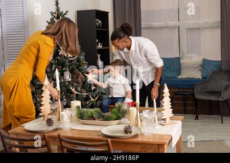 Une jeune famille est la décoration d'un arbre de Noël dans la salle de séjour. Banque D'Images