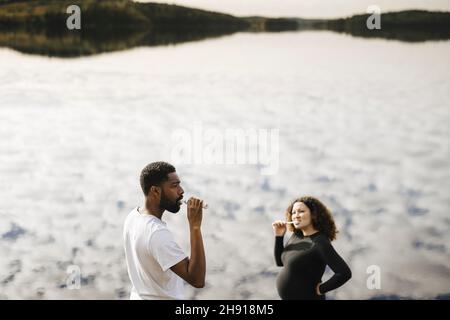 Une jeune femme enceinte se brossant les dents avec un petit ami le matin contre le lac Banque D'Images