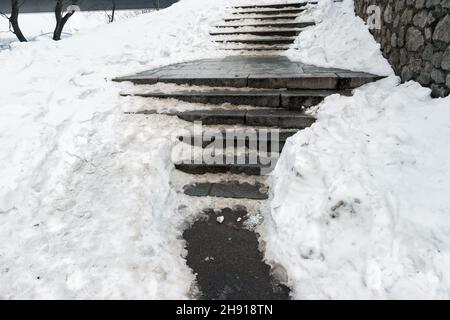 Escalier en pierre de béton recouvert de neige épaisse et glissante après une tempête de neige blizzard qui s'est abattue sur la passerelle piétonne de la ville.Risque de chute Banque D'Images