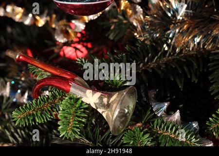 Décorations de Noël vintage comprenant une trompette ornementale et des boules sur un vrai pin Banque D'Images