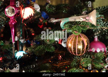 Décorations de Noël vintage comprenant une trompette ornementale et des boules sur un vrai pin Banque D'Images