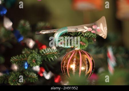 Décorations de Noël vintage comprenant une trompette ornementale et des boules sur un vrai pin Banque D'Images