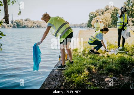 Les écologistes hommes et femmes se portent volontaires lors du nettoyage des plastiques sur les rives du lac Banque D'Images