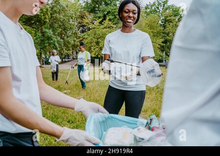 Les écologistes hommes et femmes ramassant les déchets plastiques dans le parc Banque D'Images