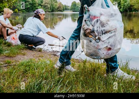 Les écologistes hommes et femmes nettoient les déchets de plastique de l'étang au parc Banque D'Images