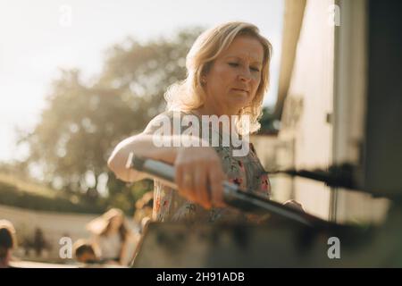 Femme mûre préparant des aliments sur le barbecue pendant le dîner Banque D'Images