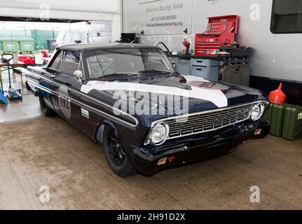 Vue des trois quarts avant d'un Bleu foncé, 1964 Ford Falcon, dans le garage à fosse de l'équipe de course historique, au Silverstone Classic 2021 Banque D'Images