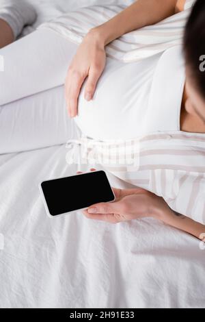 vue de dessus d'une femme enceinte avec un smartphone et un écran vide Banque D'Images