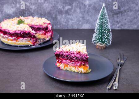 Salade de hareng sous un manteau de fourrure. Salade russe traditionnelle composée de plusieurs couches de hareng, de betteraves, de pommes de terre, de carottes et d'œufs. Petit arbre de Noël. Gros plan Banque D'Images