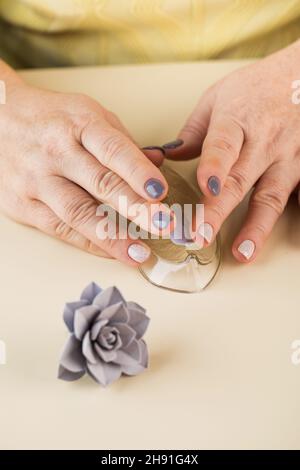 Le maître sculpte un pétale à partir d'argile polymère pour créer une fleur décorative. Banque D'Images