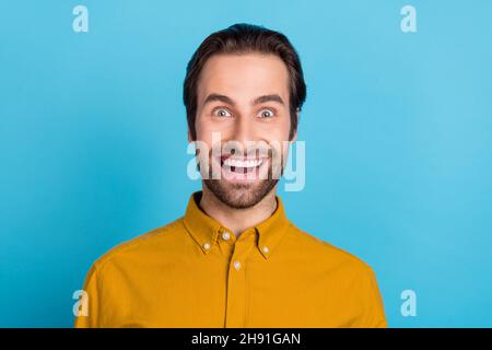 Photo de brunet millénaire impressionné gars porter une chemise jaune isolé sur fond bleu Banque D'Images