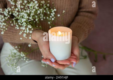Femme tenant une bougie allumée.Femmes mains et bougie gros plan. Banque D'Images