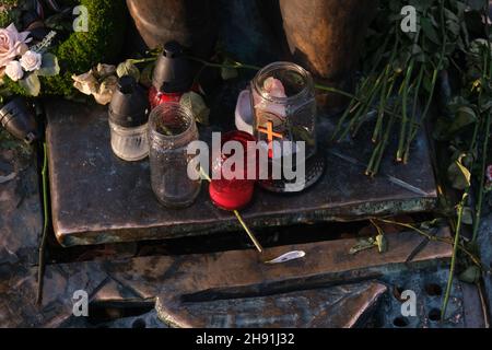 Pots en verre avec une croix chrétienne et des fleurs au mémorial. Banque D'Images