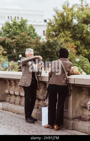 Homme senior photographiant la femme à travers la caméra sur le pont pendant le week-end Banque D'Images