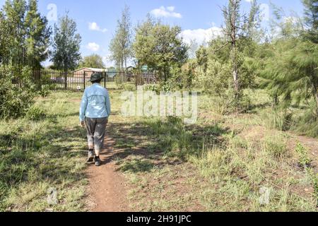 Une randonneur femelle énergique et déterminée avec un chapeau marchant sur un chemin près d'une clôture dans les Meadows d'une ferme dans l'est de Pretoria Afrique du Sud Banque D'Images