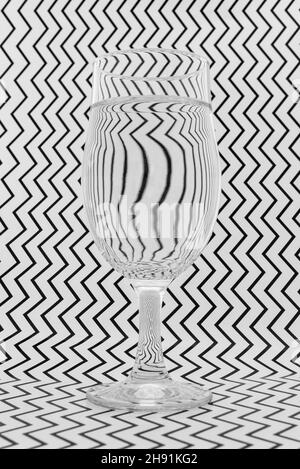 Image artistique de papier à motifs noir et blanc se réfractant à travers un verre et créant des motifs et des formes intéressants. Banque D'Images