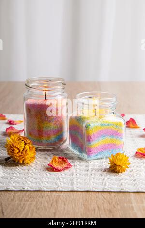 Les enfants ont fait des bougies en poudre de cire colorées dans la maison en versant de la poudre dans le vieux pot de nourriture pour bébé et en insérant la mèche à l'intérieur, un arrière-plan minimal. Banque D'Images