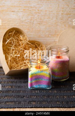 Les enfants ont fait des bougies en poudre de cire colorées dans la maison en versant de la poudre dans le vieux pot de nourriture pour bébé et en insérant la mèche à l'intérieur.Concept de passe-temps. Banque D'Images