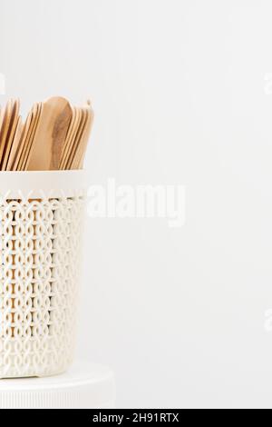 Bâtonnets de bois pour cire dans un panier blanc isolé sur fond blanc avec espace de copie Banque D'Images