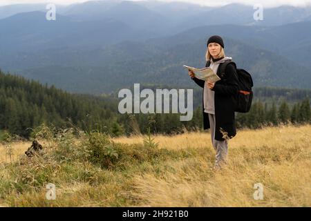 Fille touriste dans la montagne lire la carte, femme voyageur avec une carte dans les mains, arrière-plan des montagnes, chaîne de montagnes de Roumanie, concept de voyage touristique. Banque D'Images