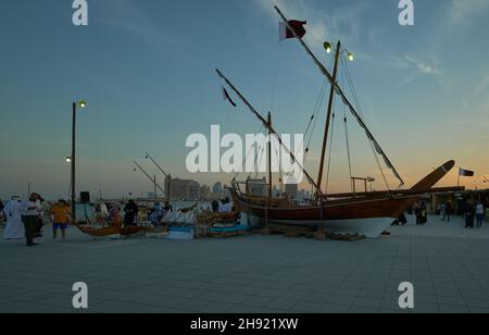 Katara onzième festival traditionnel de dhow à Doha Qatar vue au coucher du soleil montrant le dhow avec les drapeaux du Qatar exposés sur la plage avec les habitants et les visiteurs Banque D'Images