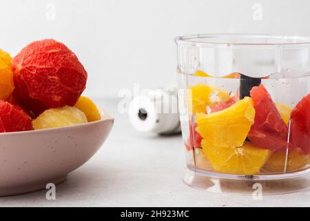 Pamplemousse, bonbons et oranges pelés dans une assiette, bol mélangeur avec fruits, pour un smoothie aux agrumes sain Banque D'Images