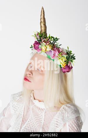 Portrait d'une femme albinos dans une couronne avec fleurs et corne isolée sur blanc Banque D'Images