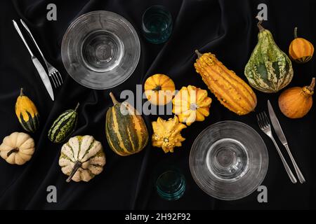 la table est recouverte d'une nappe noire d'halloween avec des citrouilles et un ensemble d'assiettes et de couverts Banque D'Images