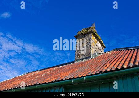 Vue sur le toit en fonte ondulée rouillée et la cheminée en pierre d'une ancienne lande bothy dans le Perthshire, Bright Sunlight, Écosse Royaume-Uni Banque D'Images