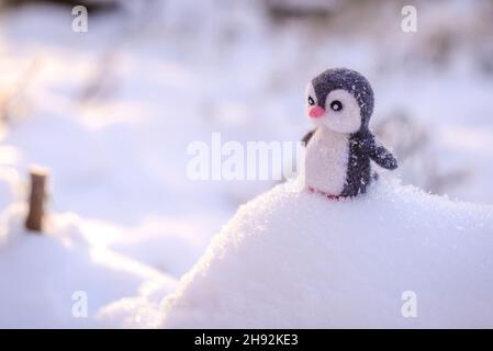 Pingouin en peluche fait main en laine en hiver sur un toboggan Banque D'Images