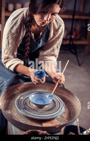 Mains des femmes. Potter au travail. Création de plats. Roue de Potter. Mains sales dans l'argile et la roue de potier avec le produit. Création. En fonctionnement Banque D'Images