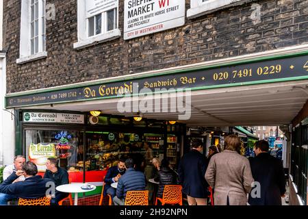 Personnes assises devant le Da Corradi Sandwich Bar à l'entrée du marché Shepherd, Londres, Royaume-Uni. Banque D'Images