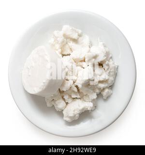 Rond de fromage de chèvre et fromage de chèvre émietté sur plaque de céramique blanche isolée sur blanc.Vue de dessus. Banque D'Images