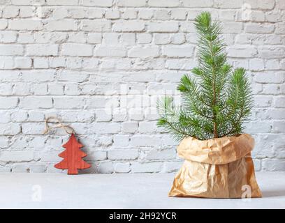 Mini arbre de Noël dans un sac en papier sur le fond du mur de briques, zéro déchet Banque D'Images