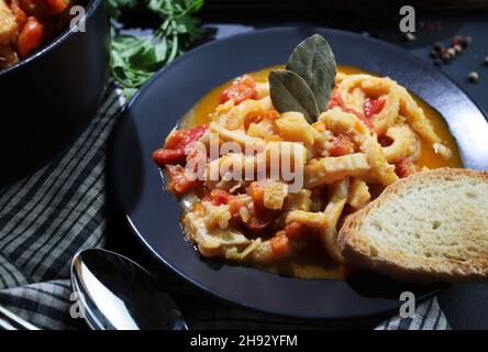 Cuisine italienne.Plat de tripe de bœuf typique avec sauce tomate et croûtons de pain dans l'assiette sur la table.Directement au-dessus. Banque D'Images
