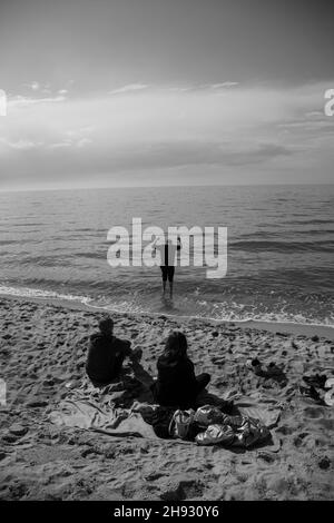 Prise de vue verticale en niveaux de gris d'un groupe de personnes passant du temps sur la plage Banque D'Images