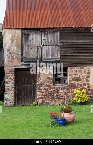 Un ancien hangar avec un toit en acier ondulé rouillé.De vieilles portes lambrissés ont voilé et abîmé au fil des années. Banque D'Images