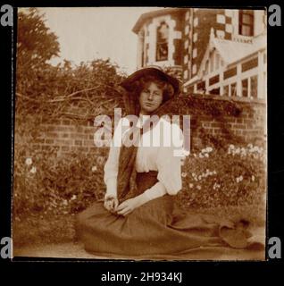 Photographie vintage de la jeune femme assise sur l'herbe dans le jardin, Edwardian, anglais, 1910 Banque D'Images