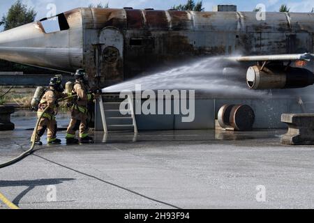 Deux pompiers du 18e Escadron de génie civil ont incendié lors d'un exercice d'entraînement conjoint avec le commandant des services d'incendie et d'urgence de la région navale du Japon à la base aérienne de Kadena, au Japon, le 30 novembre 2021.Avec l'observation des pompiers de la Force aérienne japonaise d'autodéfense, les services d'urgence d'incendie de Kadena ont joint leurs capacités aux pompiers de CNRJ pour éteindre un incendie de véhicule, un incendie de petit aéronef, un incendie de gros aéronef et des torts pendant cet événement.(É.-U.Photo de la Force aérienne par le sergent d'état-major.Savannah L. Waters) Banque D'Images