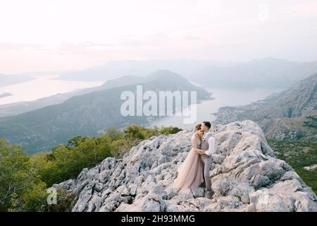 Marié embrasse la mariée sur la montagne contre le fond de la baie de Kotor.Drone Banque D'Images