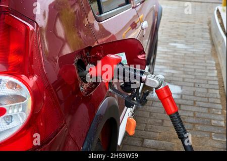 le pistolet rouge est inséré dans le réservoir à essence d'une voiture de tourisme rouge pour faire le plein d'essence Banque D'Images