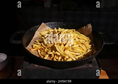 Une pile de pommes de terre frites repose sur une poêle noire Banque D'Images