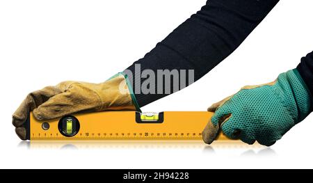 Travailleur de la construction avec gants de travail de protection, tenant un niveau à bulle orange, isolé sur fond blanc avec réflexions. Banque D'Images